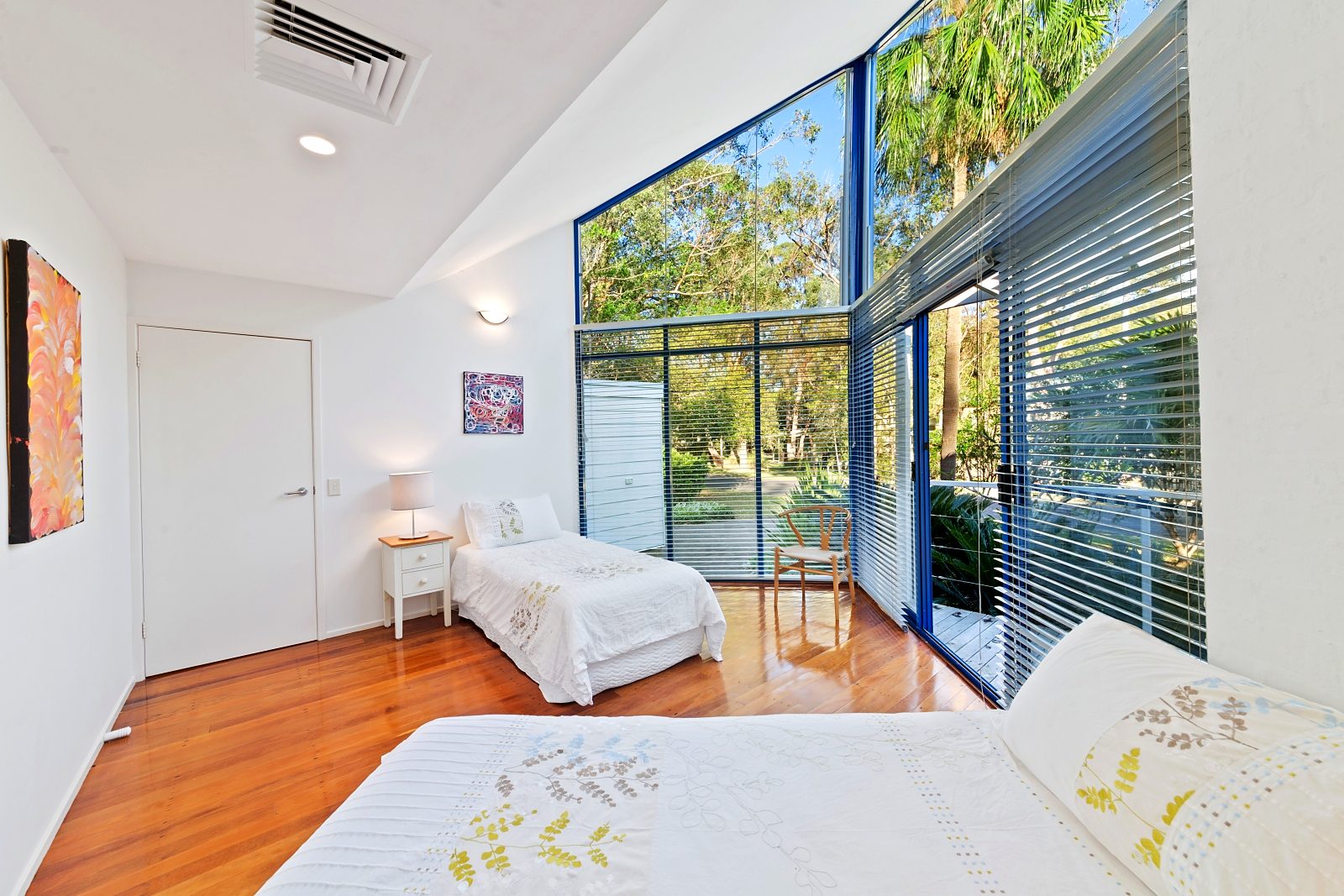 Third bedroom at Sails Pearl Beach with two single beds and a wall of glass to the bush