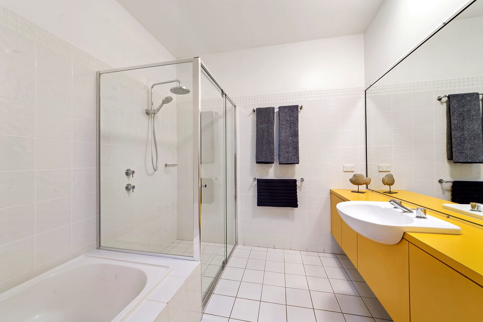 Bathroom at Sails Pearl Beach with walk-in shower, bath and yellow vanity