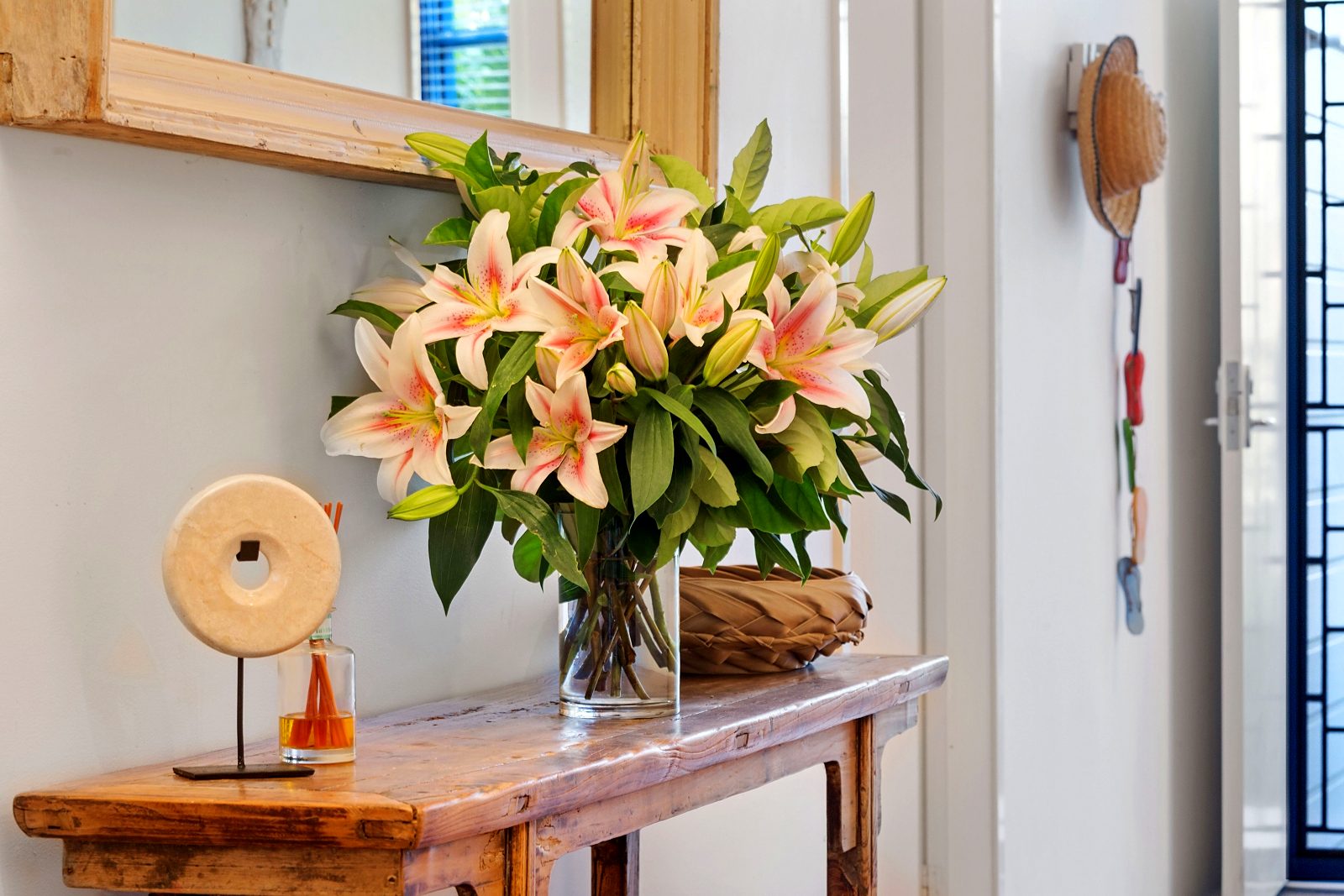 Lilies on the timber console inside the front door at Sails Pearl Beach